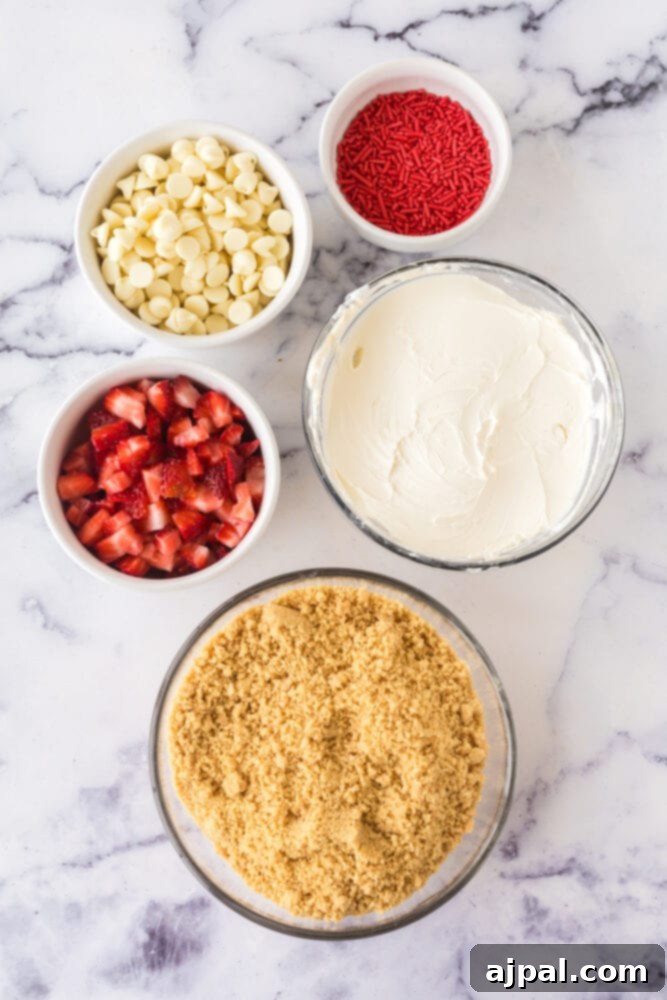 Ingredients for strawberry shortcake truffles: white chocolate chips, crushed golden Oreos, fresh diced strawberries, and red sprinkles laid out on a table.