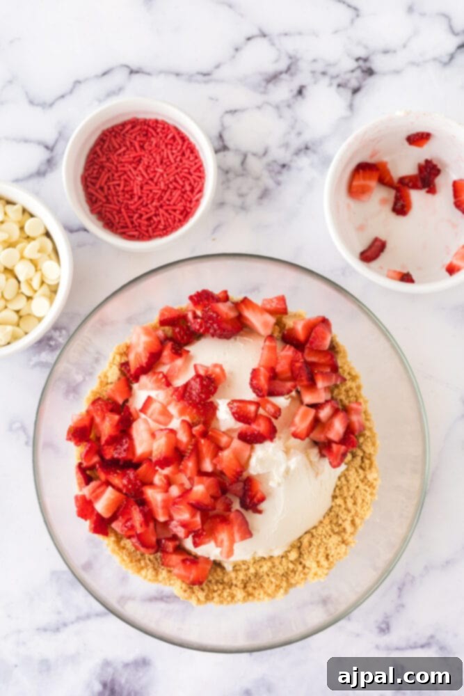 A bowl holds a mixture of crushed golden Oreos, white chocolate chips, and diced strawberries, ready to be combined into truffle batter.