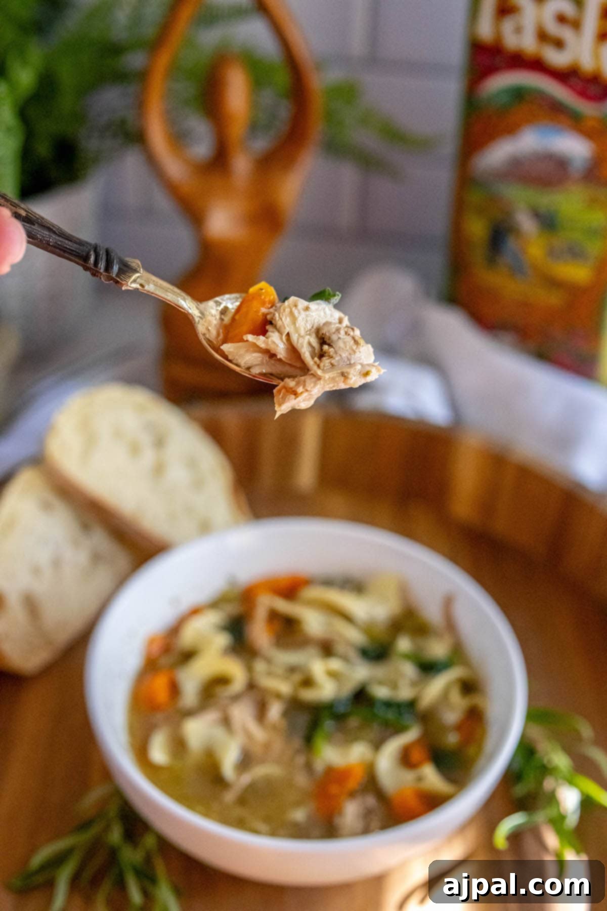 Hearty Slow Cooker Turkey Noodle Soup 3 A spoon lifting turkey, carrots, and spinach from a bowl of slow cooker turkey noodle soup, highlighting the delicious ingredients.