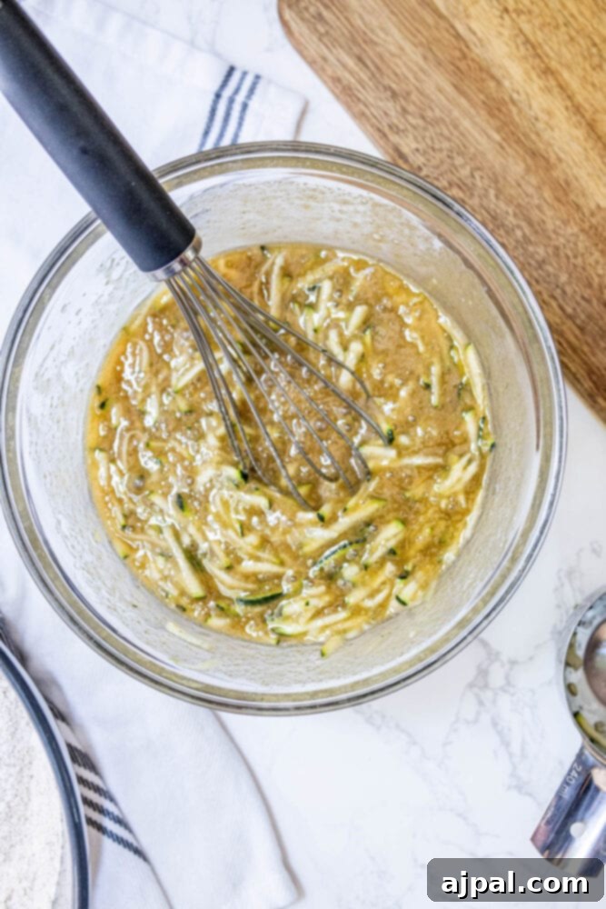 zucchini shreds mixed into bread batter in a glass bowl