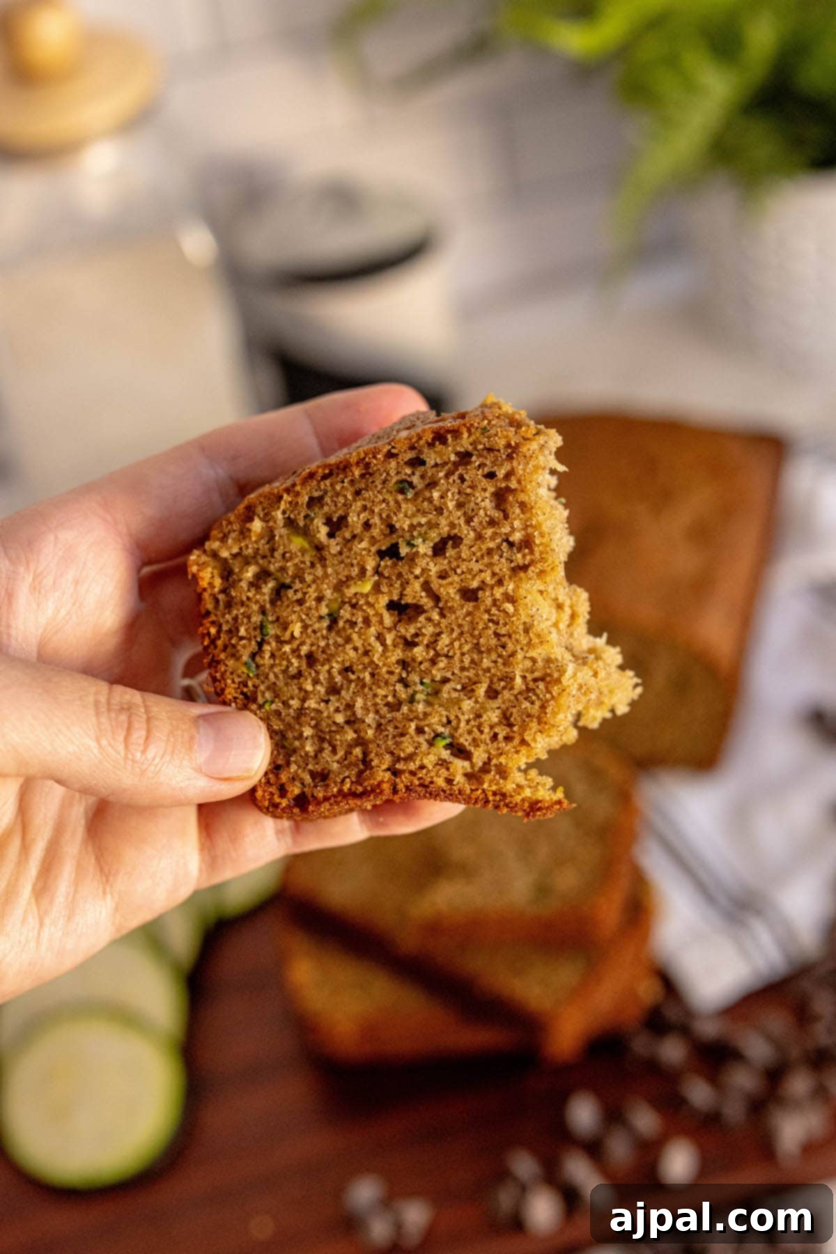 a hand holding a piece of zucchini bread