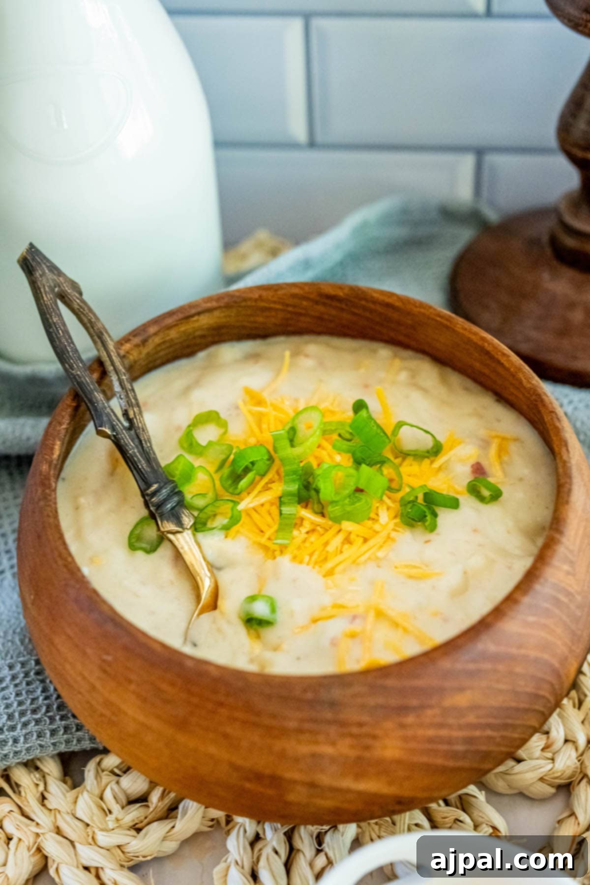 Creamy Slow Cooker Loaded Baked Potato Soup 2 Creamy loaded baked potato soup garnished with bacon and chives in a rustic wooden bowl