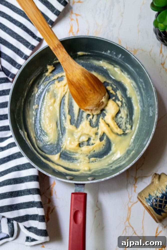 Creamy Slow Cooker Loaded Baked Potato Soup 6 A golden-brown roux simmering in a saucepan on the stovetop.
