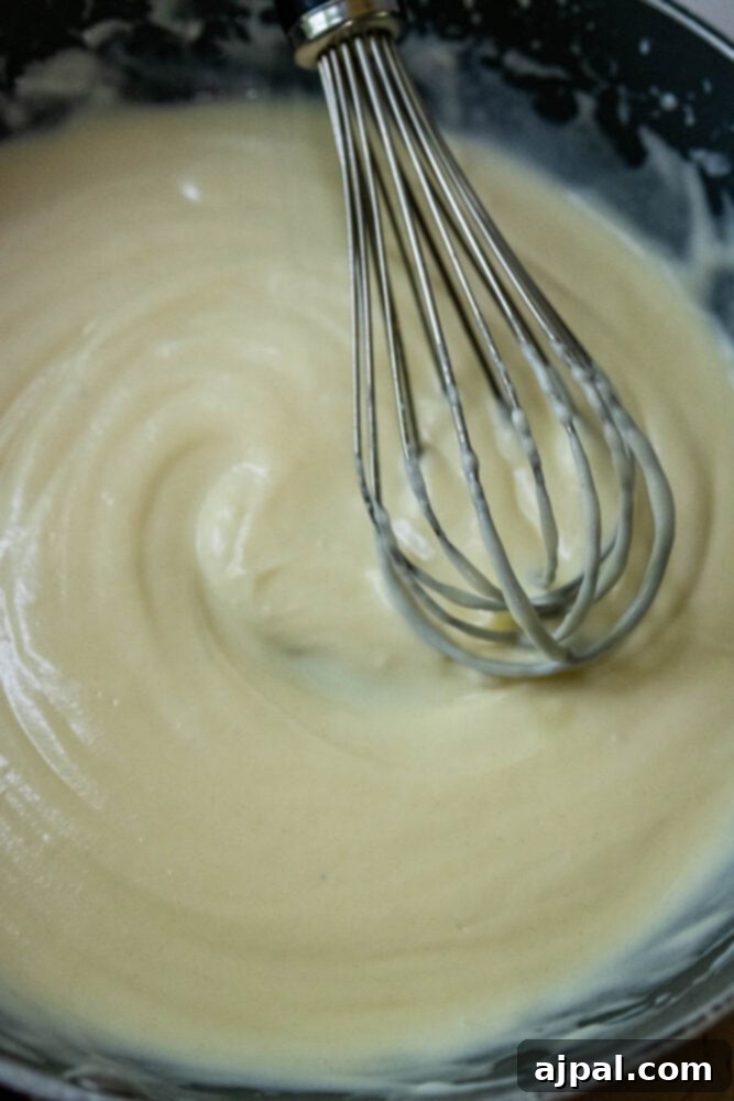Creamy Slow Cooker Loaded Baked Potato Soup 7 A whisk stirring the roux in a pan, ensuring a smooth consistency.