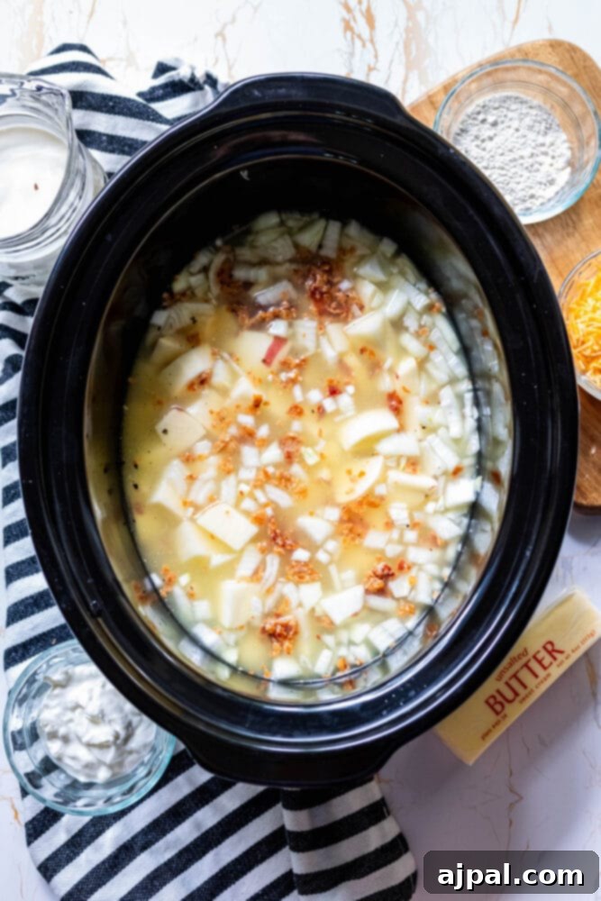 Creamy Slow Cooker Loaded Baked Potato Soup 8 The potato soup simmering gently in a slow cooker, nearly ready.