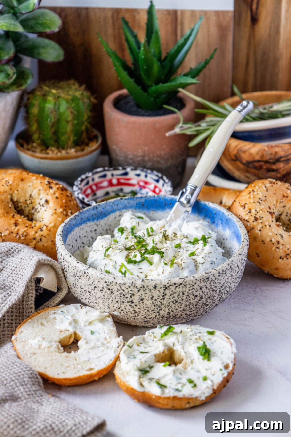A vibrant bowl of garlic dill schmear with a side of everything bagels, artfully arranged on a table.