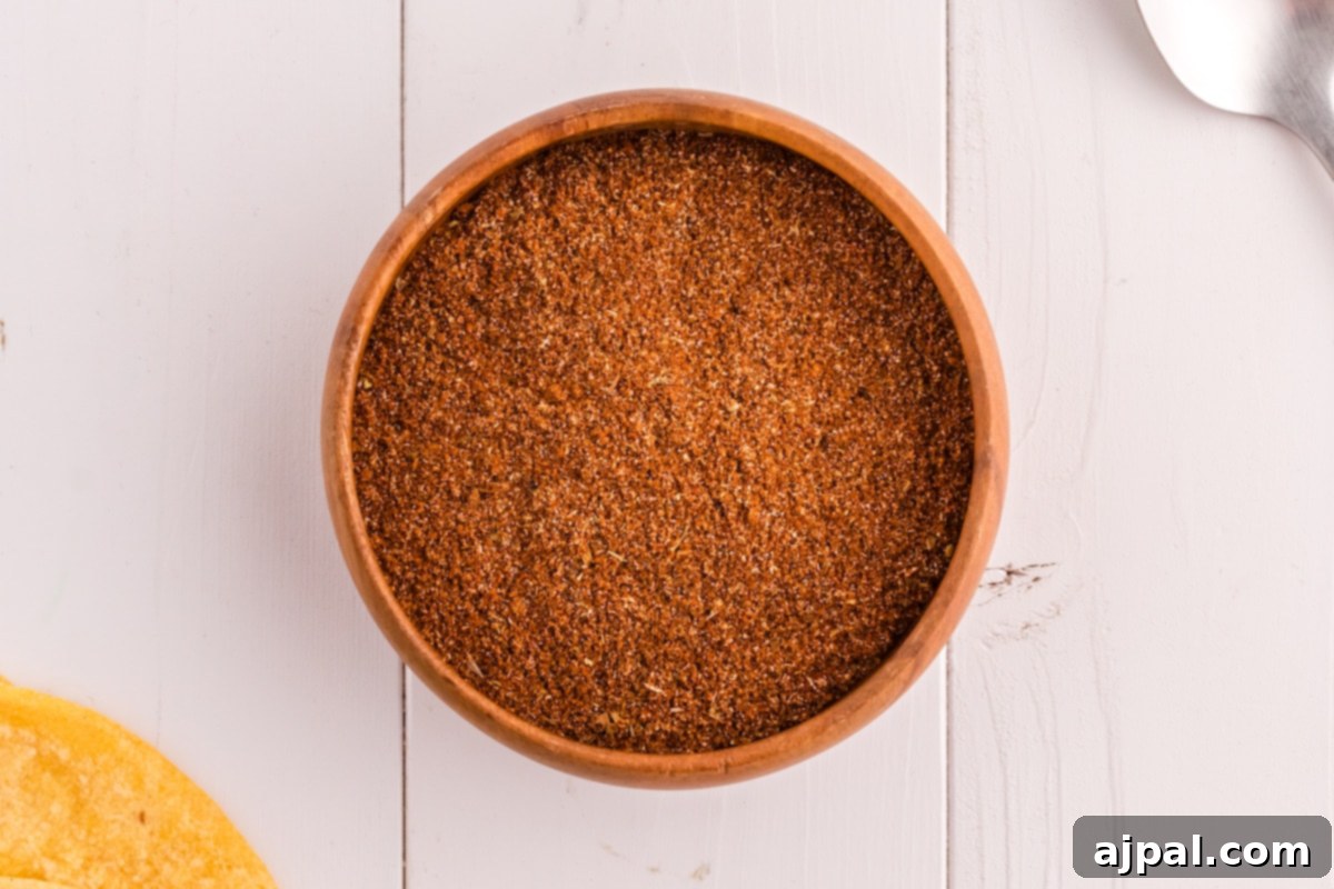 Taco Spice Blend 3 Taco seasoning mix in a rustic wooden bowl, next to a wooden spoon, ready for cooking