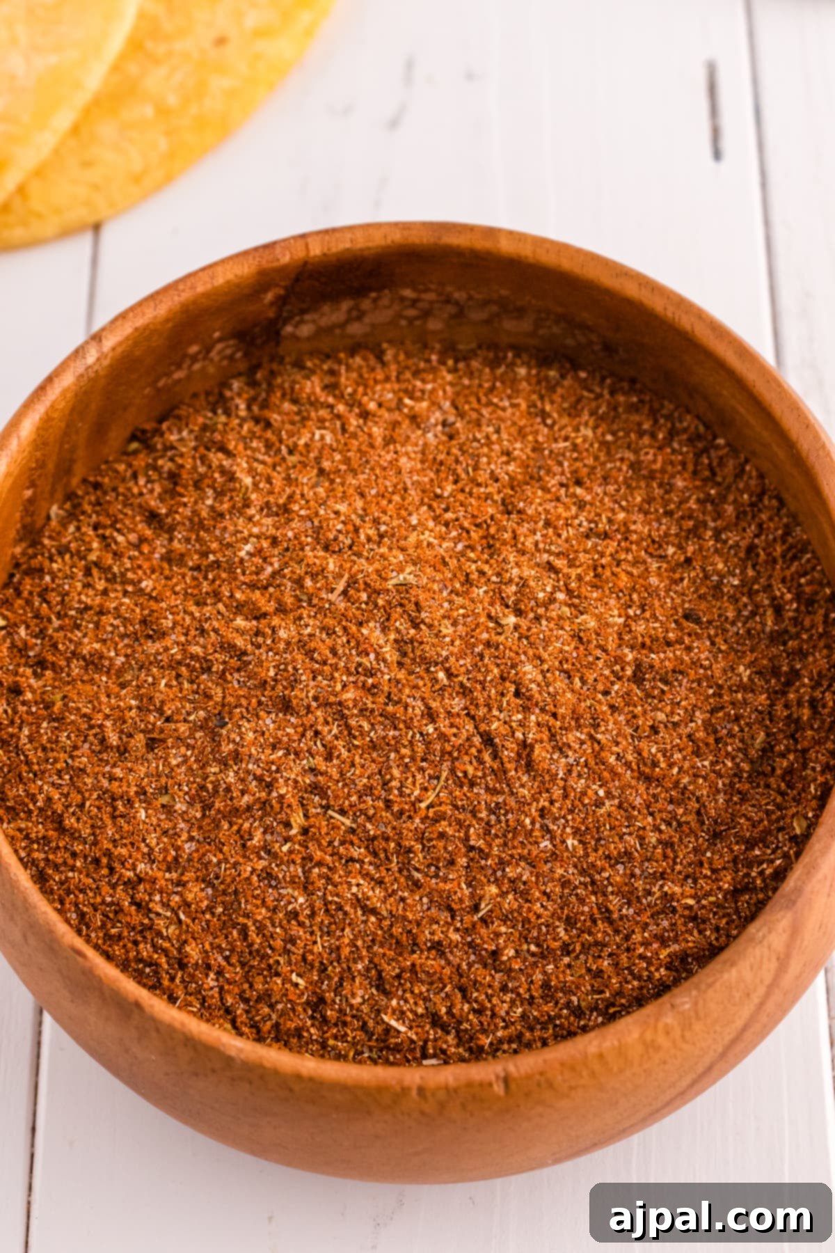 Taco Spice Blend 8 Homemade taco seasoning mix with visible chili powder in a wooden bowl on a white table