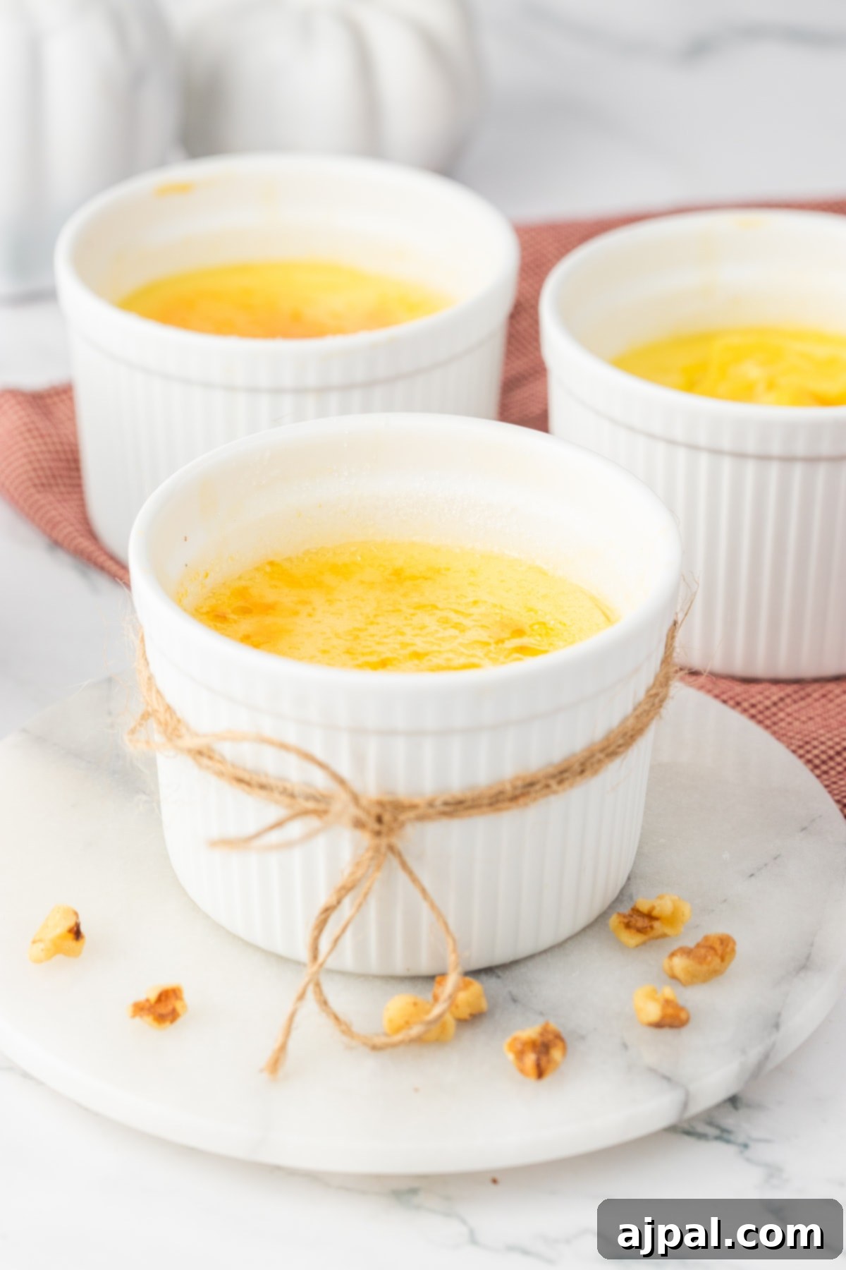Your Instant Pot's Secret to Perfect Creme Brulee 3 Creme Brûlée in small white ramekins with a twine rope tied around the cups.
