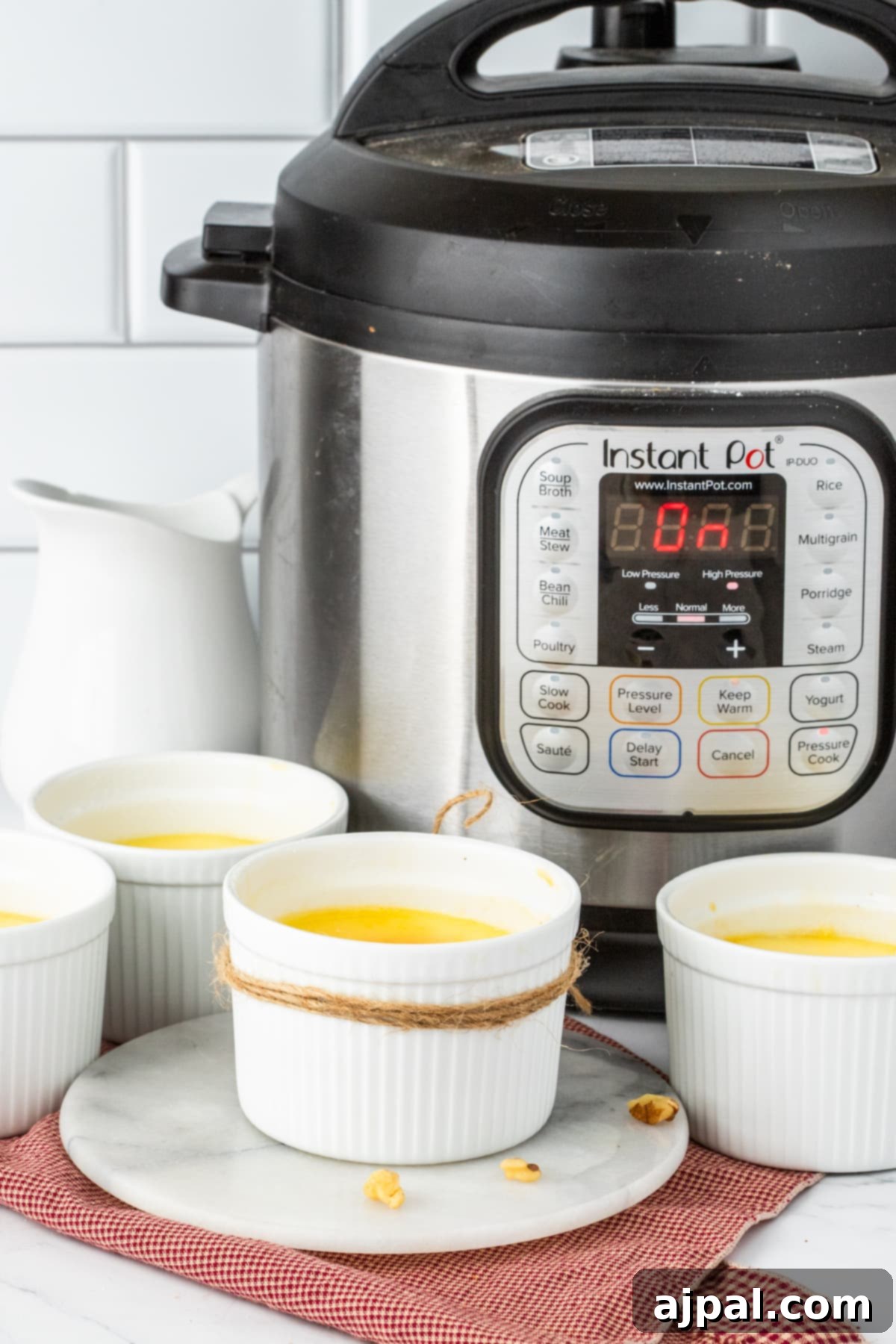 Your Instant Pot's Secret to Perfect Creme Brulee 17 Creme Brûlée in small white ramekins with a twine rope tied around the cups in front of an Instant Pot