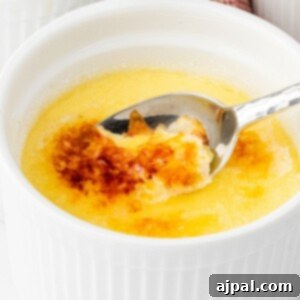 Your Instant Pot's Secret to Perfect Creme Brulee 19 a spoon scooping burnt sugar topping of a creme brûlée in a white ramekin