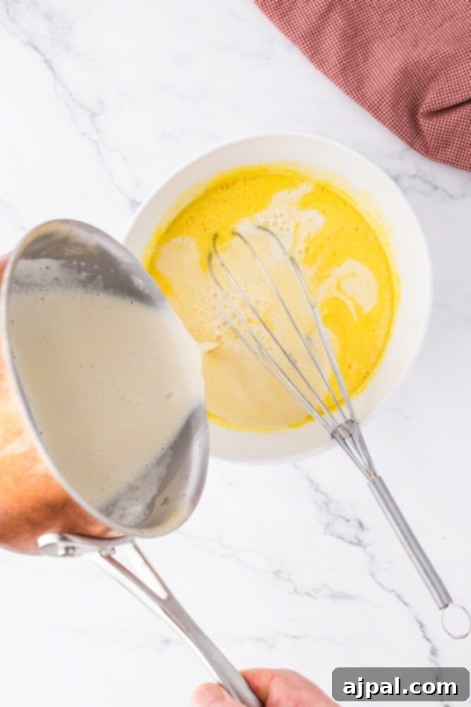Your Instant Pot's Secret to Perfect Creme Brulee 8 a pott pouring warmed milk into egg and sugar mixture in a bowl