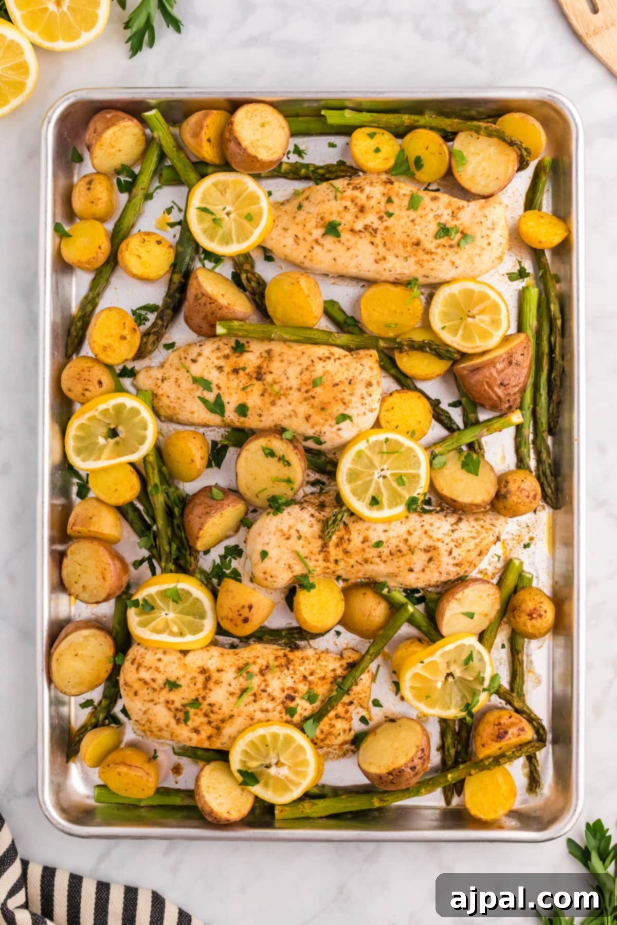 A sheet pan with baked lemon garlic chicken, potatoes, and asparagus, ready to be served.