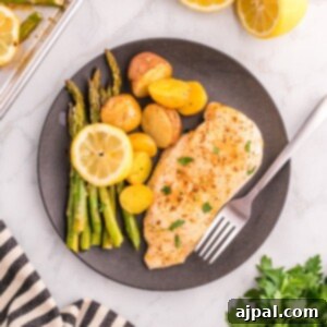 baked chicken breasts, lemon slices potatoes, and asparagus on a baking sheet
