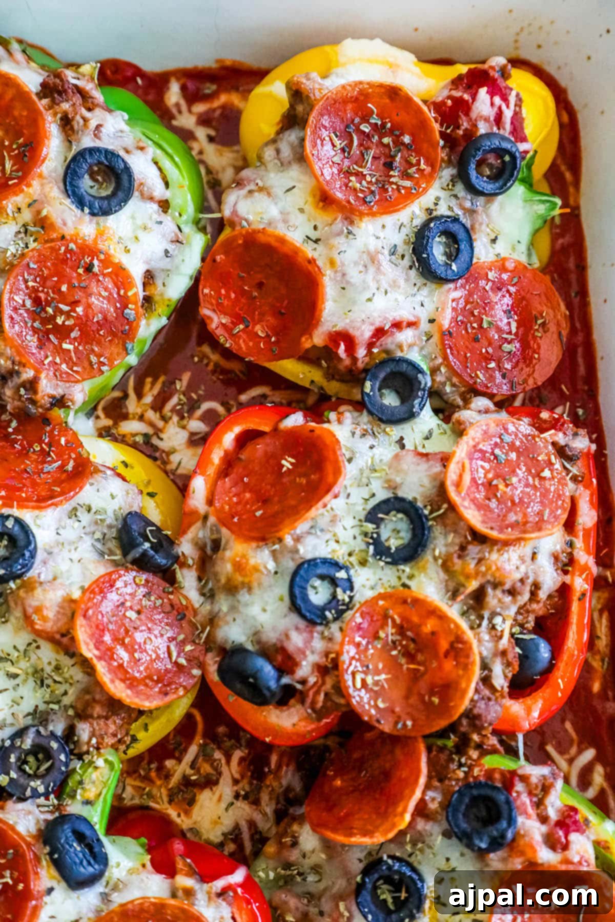Pepper Pizzas 2 Bell peppers filled with pizza toppings over marinara sauce in a white pan, highlighting a healthy low-carb pizza alternative.