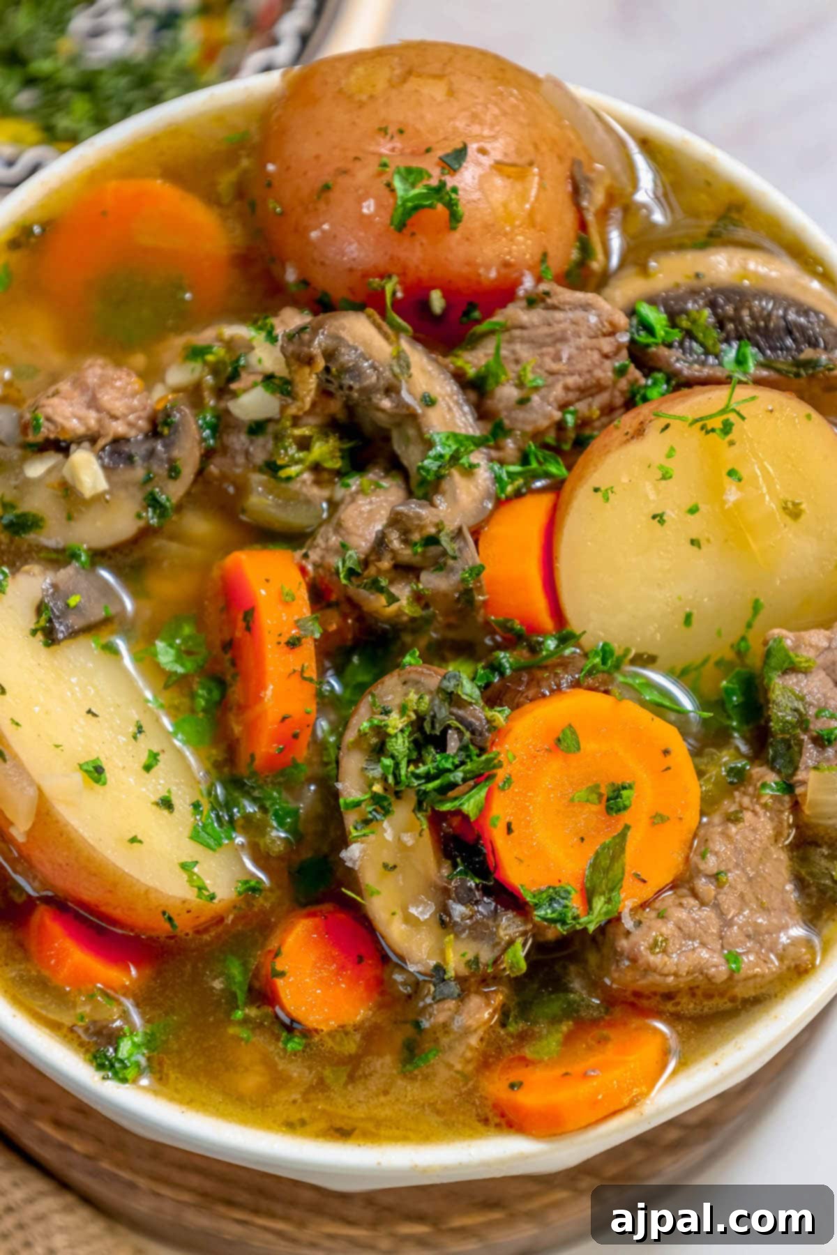 Hearty Beef and Potato Beer Stew 2 A bowl of rich steak and potato beer stew, garnished with fresh parsley.