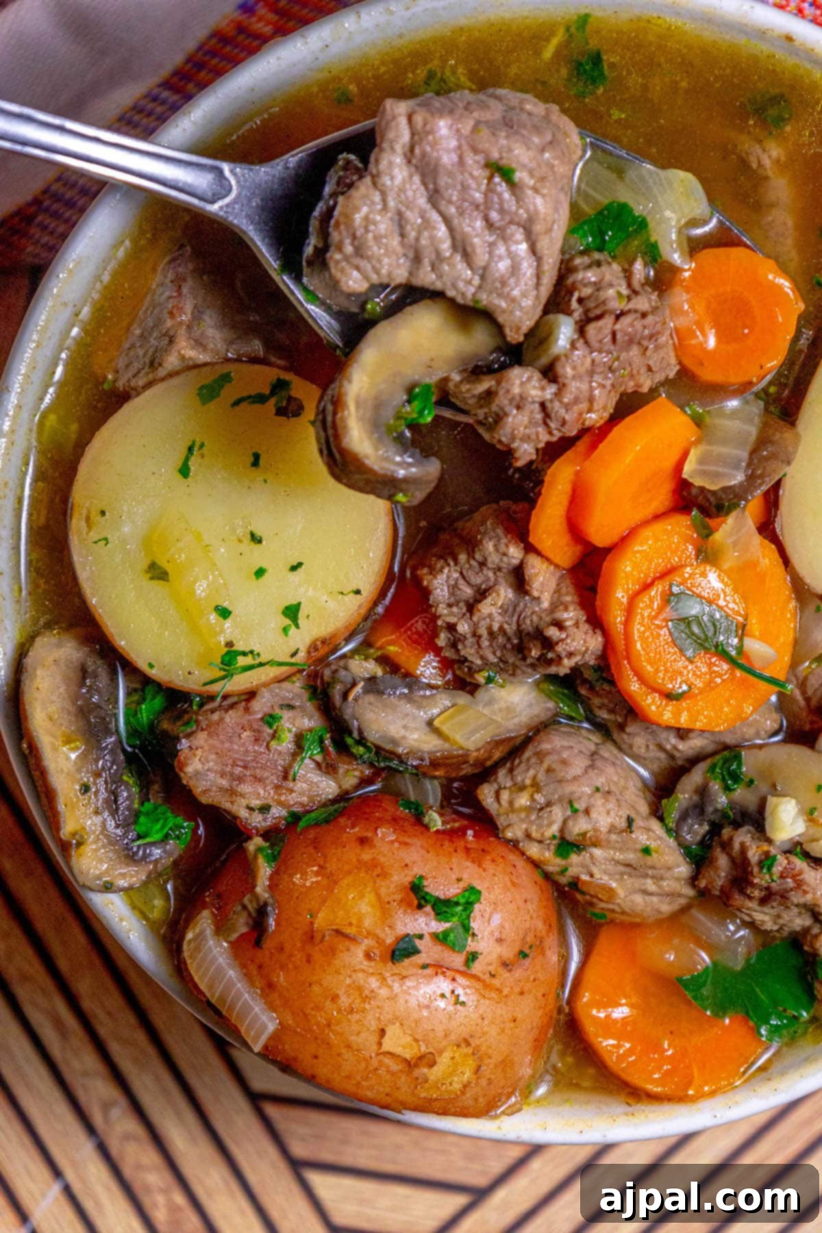 Hearty Beef and Potato Beer Stew 13 A spoon scooping a generous portion of steak and potato beer stew, showcasing the tender meat and vegetables.