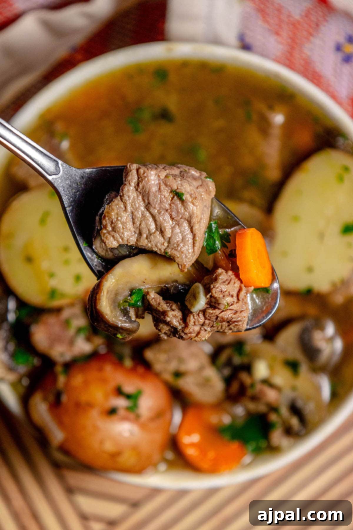 Hearty Beef and Potato Beer Stew 15 A bowl of delicious steak and potato beer stew, garnished with herbs, and ready to be enjoyed with a spoon.