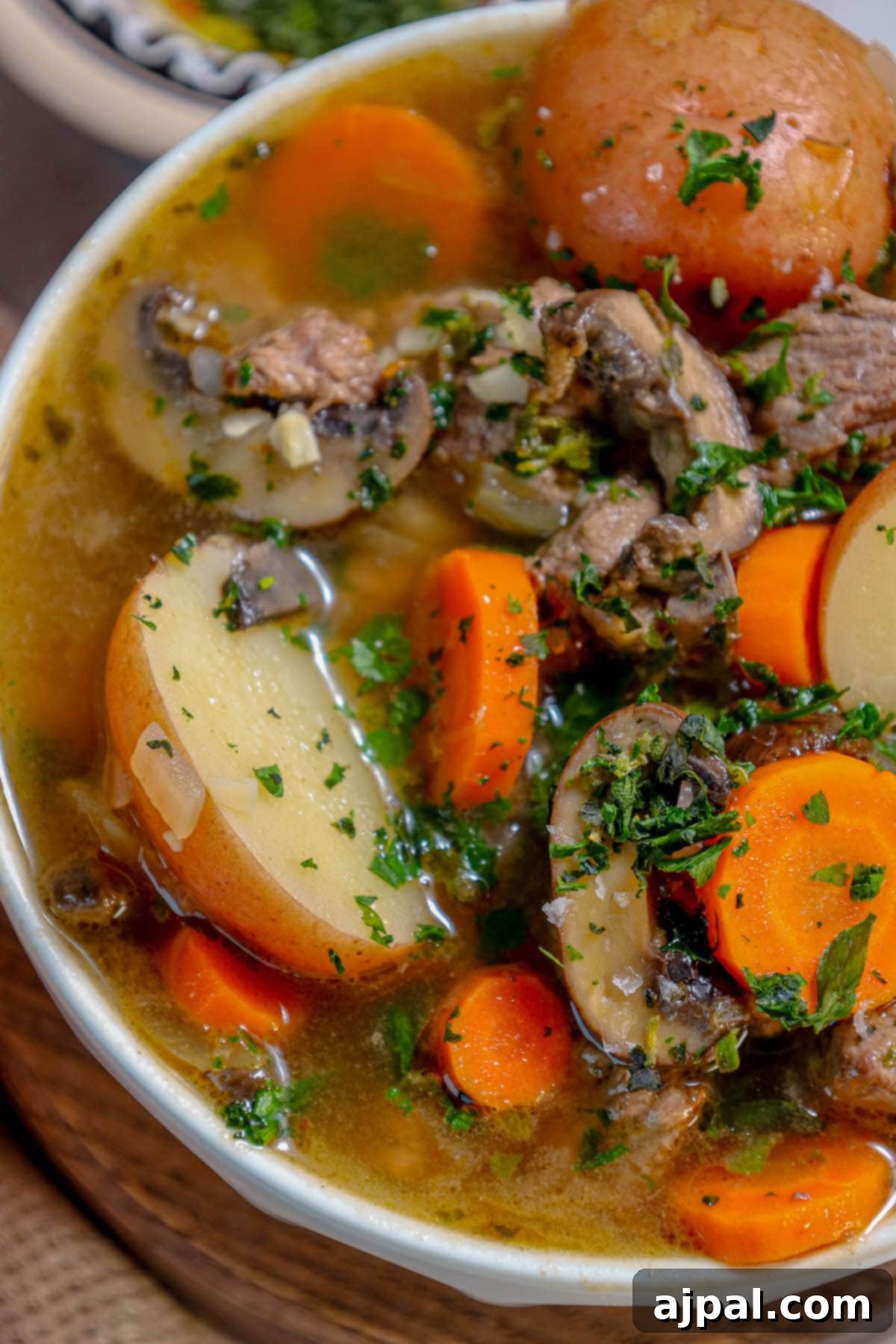 Hearty Beef and Potato Beer Stew 4 A large pot of simmering steak and potato beer stew with carrots and broth.