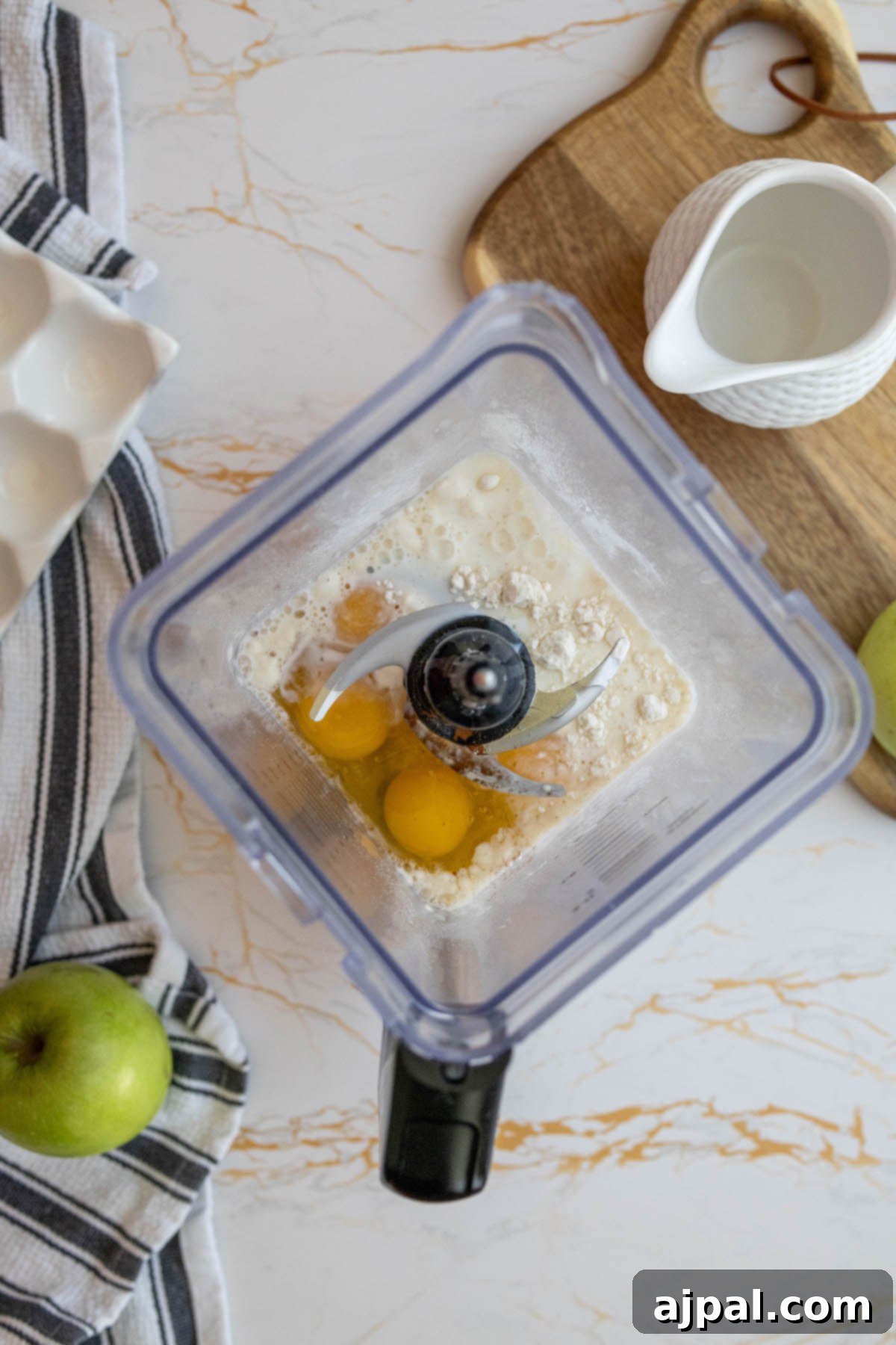 A blender filled with the creamy, light yellow batter ingredients for the Dutch baby pancake, showcasing a smooth mixture of eggs, flour, and sugar.