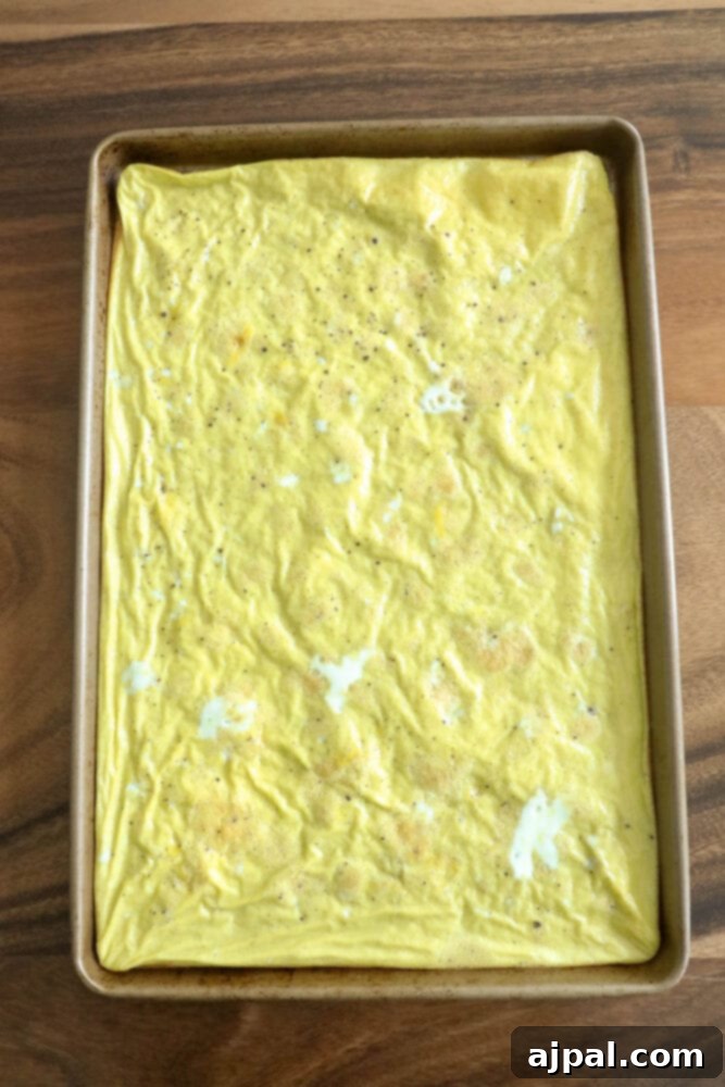 Grab-and-Go Egg Muffin Sandwiches 6 A sheet pan filled with a perfectly cooked, golden scrambled egg mixture, cut into square patties, ready for assembling homemade breakfast sandwiches.