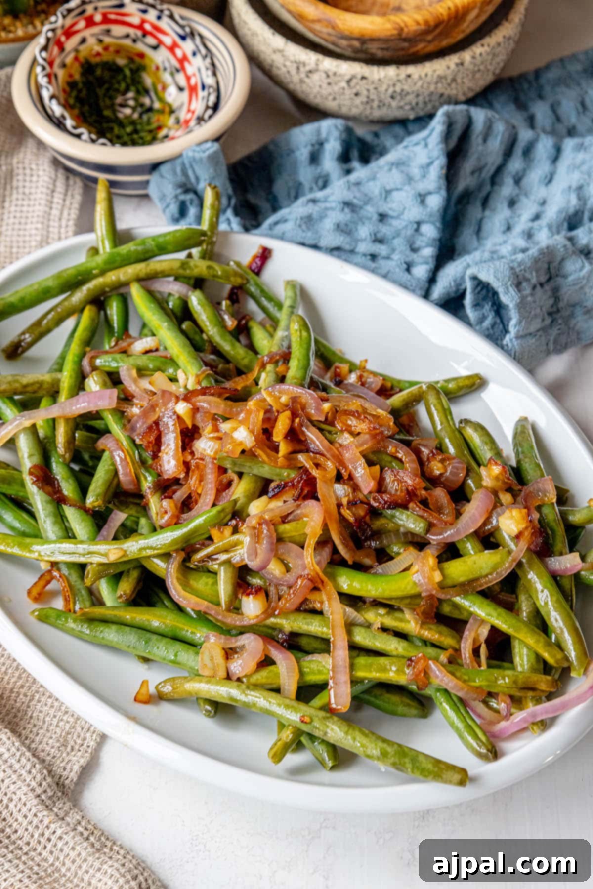 Sautéed green beans and red onion on a table.