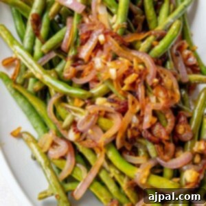 Sautéed green beans and red onion on a white plate.