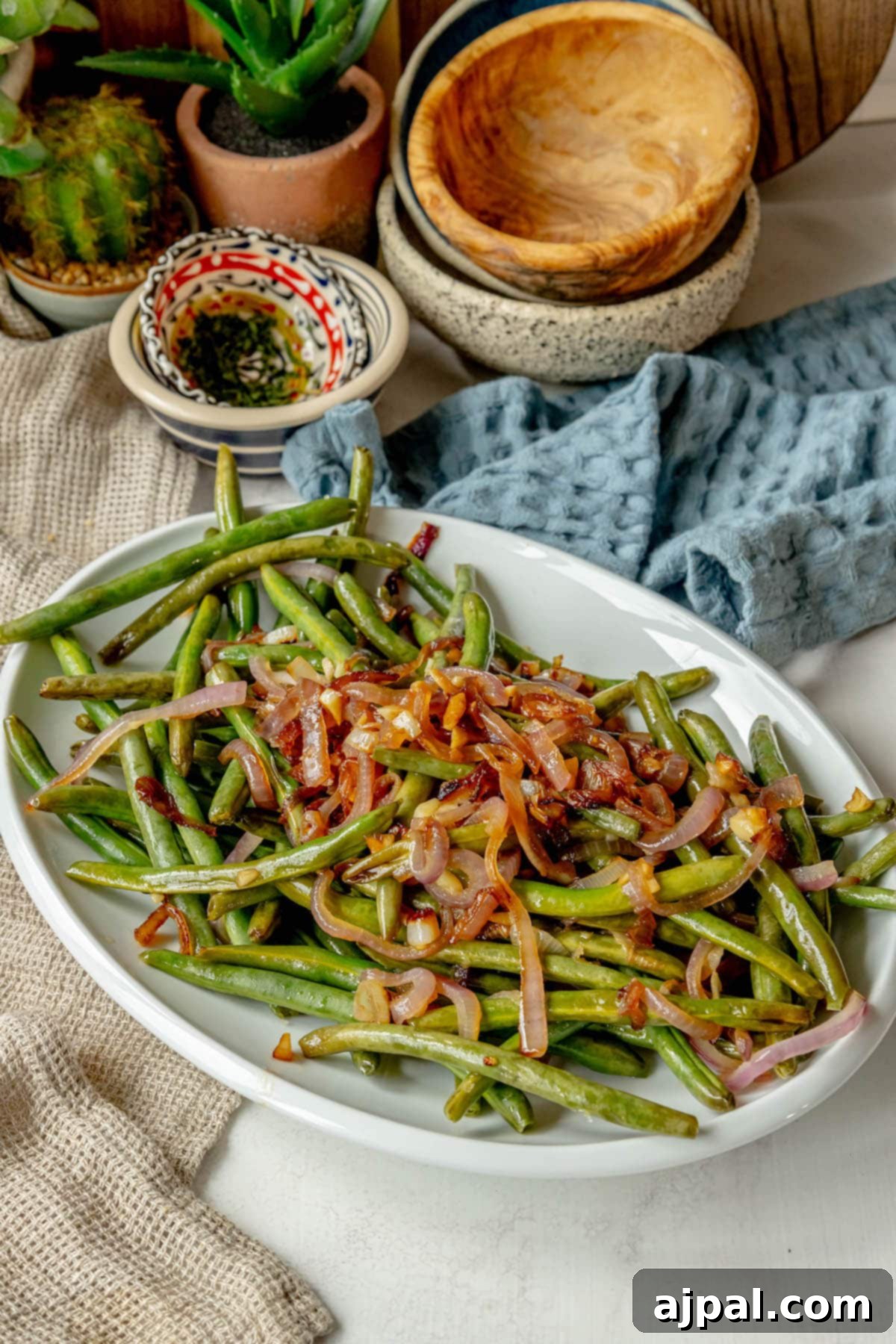 Sautéed green beans and red onion served on a white plate.