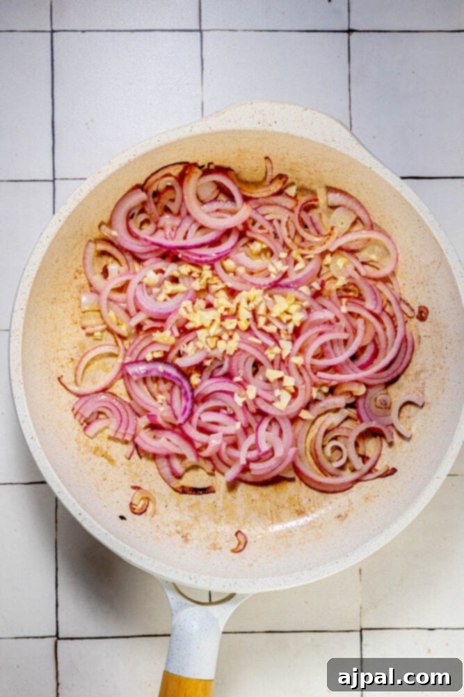 A sizzling frying pan with sautéed green beans and red onion.