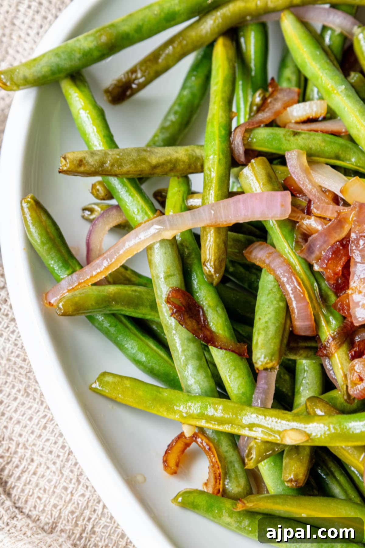 A plate with sautéed green beans and red onion.