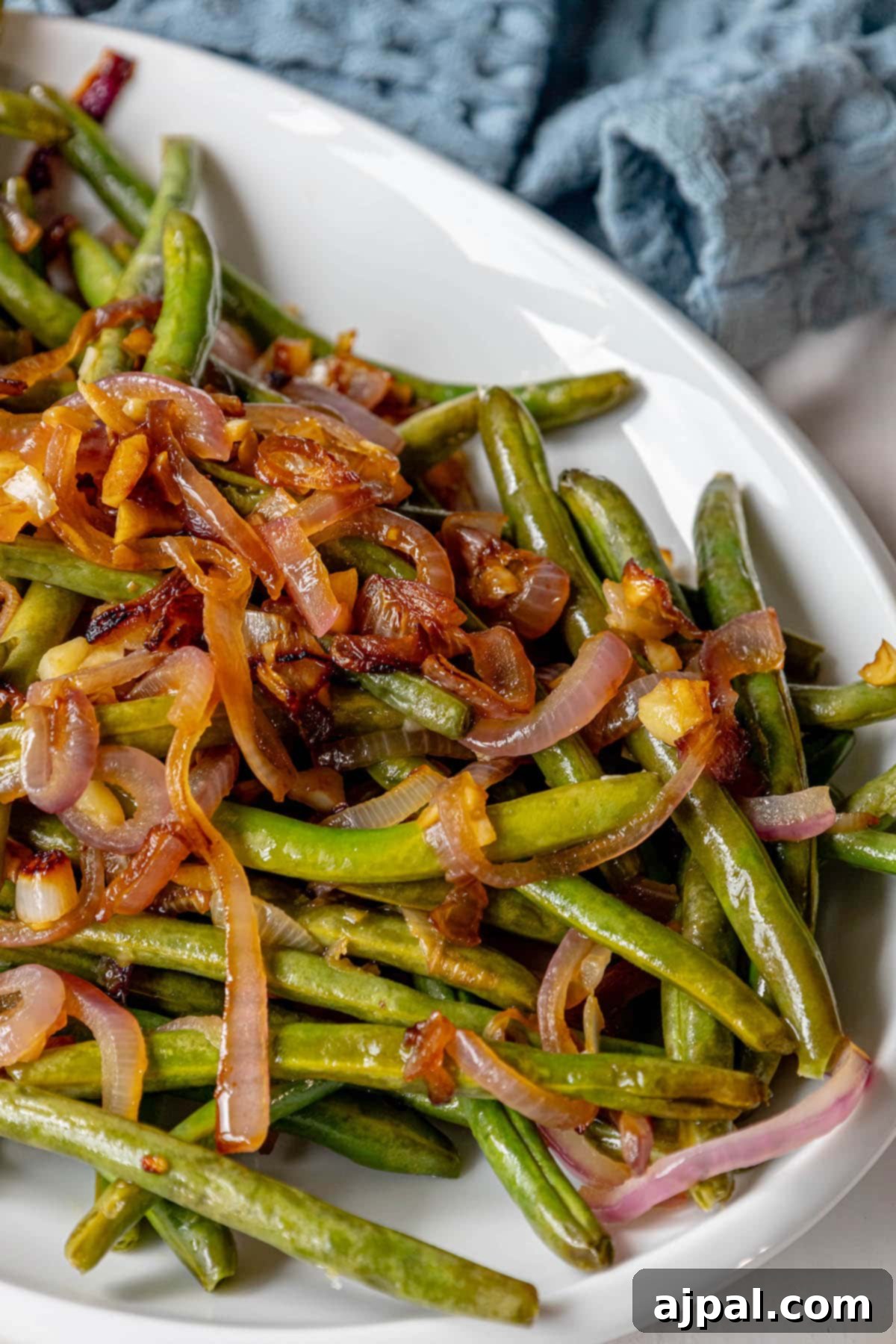 Sautéed green beans and red onion displayed on a white plate.