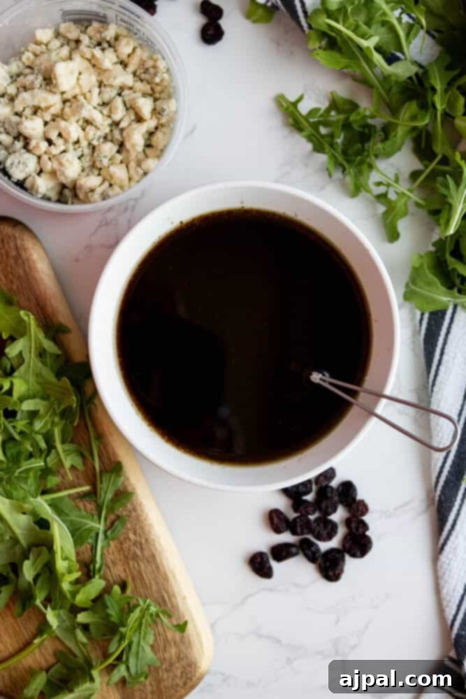 A bowl of arugula, cranberries, and blue cheese dressing with walnuts, ready to be tossed.
