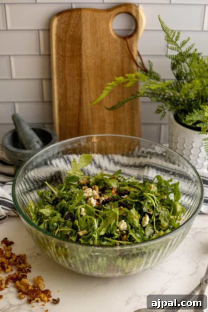 A beautiful cranberry salad with arugula and walnuts in a elegant glass bowl.