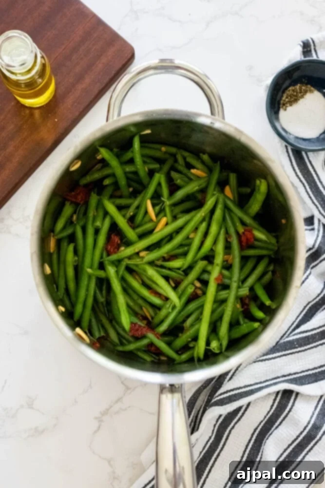 Sun-Dried Tomato & Parmesan Green Beans 6 Cheesy green beans in a pan on a white table.