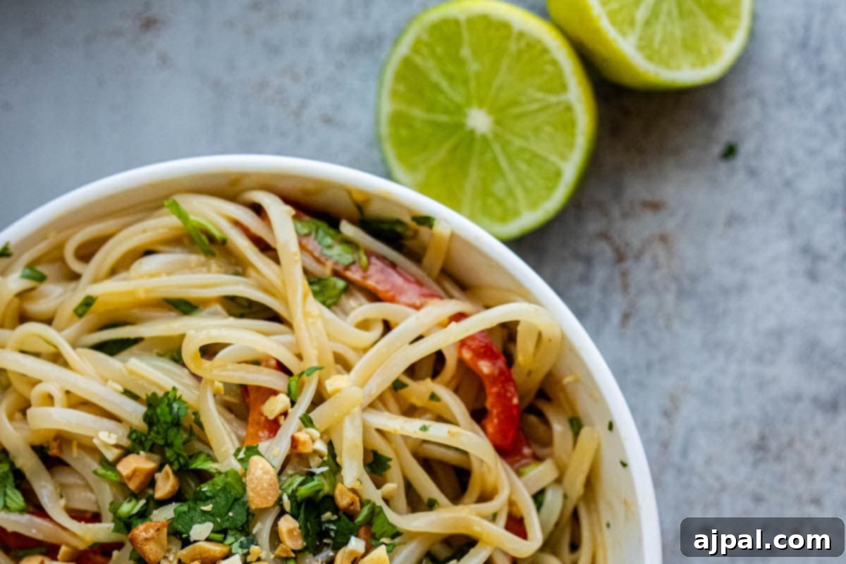 A vibrant bowl of noodles, fresh limes, crunchy peanuts, and aromatic cilantro.