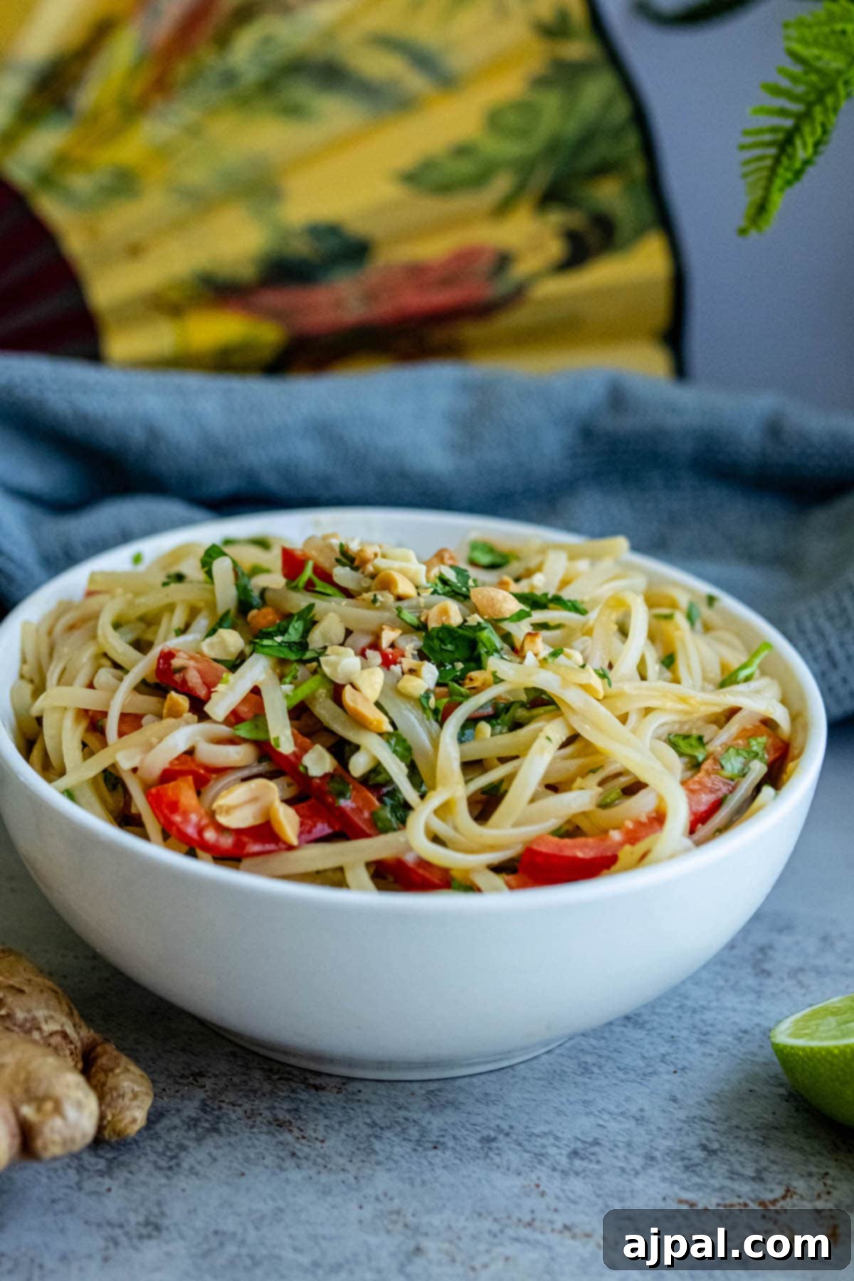 White bowl of noodles, bell peppers, and fresh cilantro, perfectly tossed in a flavorful miso dressing.