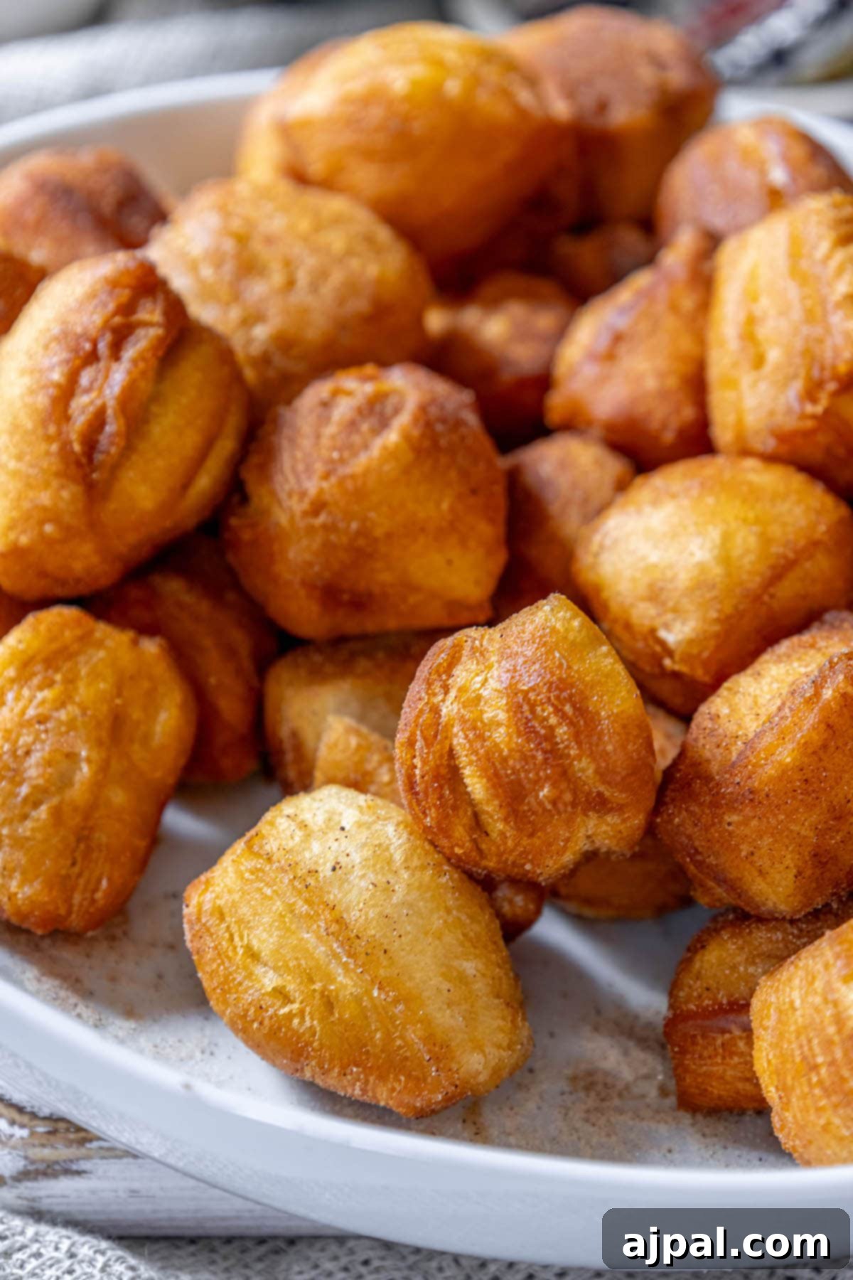 Golden Cinnamon Bites 4 Fried cinnamon doughnuts on a white plate.