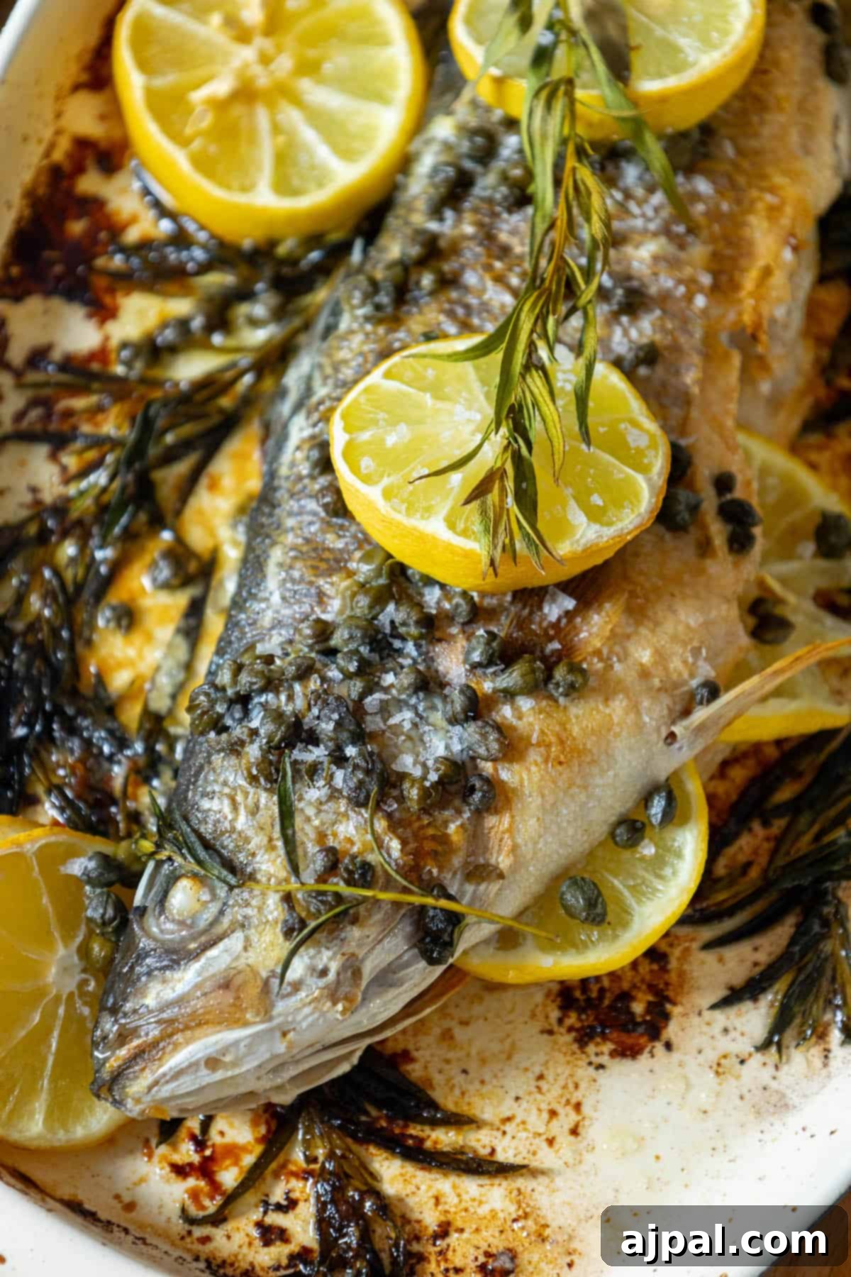Roasted Branzino with Zesty Lemon-Caper Butter 2 A perfectly roasted Branzino adorned with vibrant lemon slices and fresh herbs, presented on a pristine white plate.