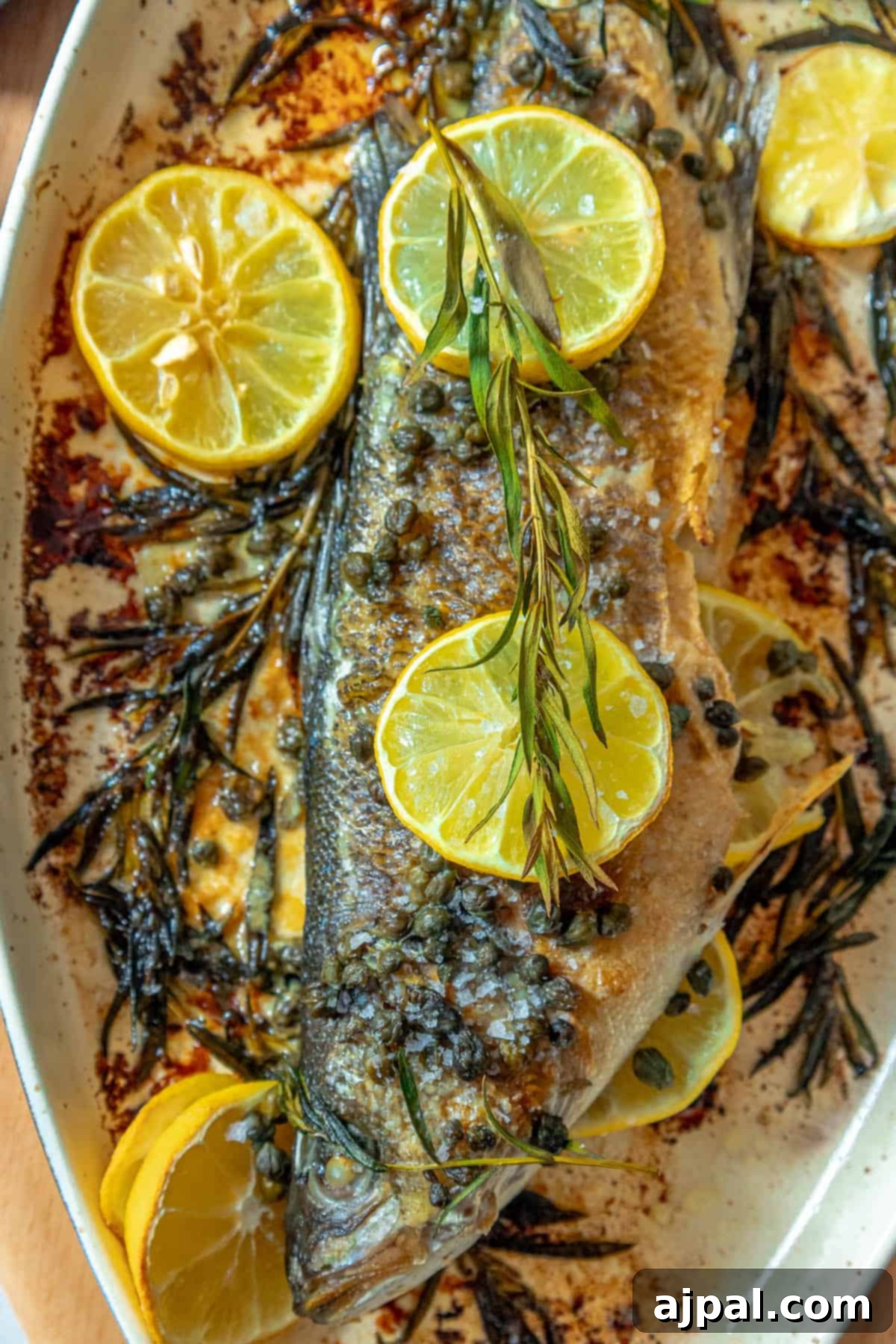Roasted Branzino with Zesty Lemon-Caper Butter 13 A beautifully presented Lemon Caper Butter Roasted Branzino, garnished with a sprig of rosemary, ready to be enjoyed.
