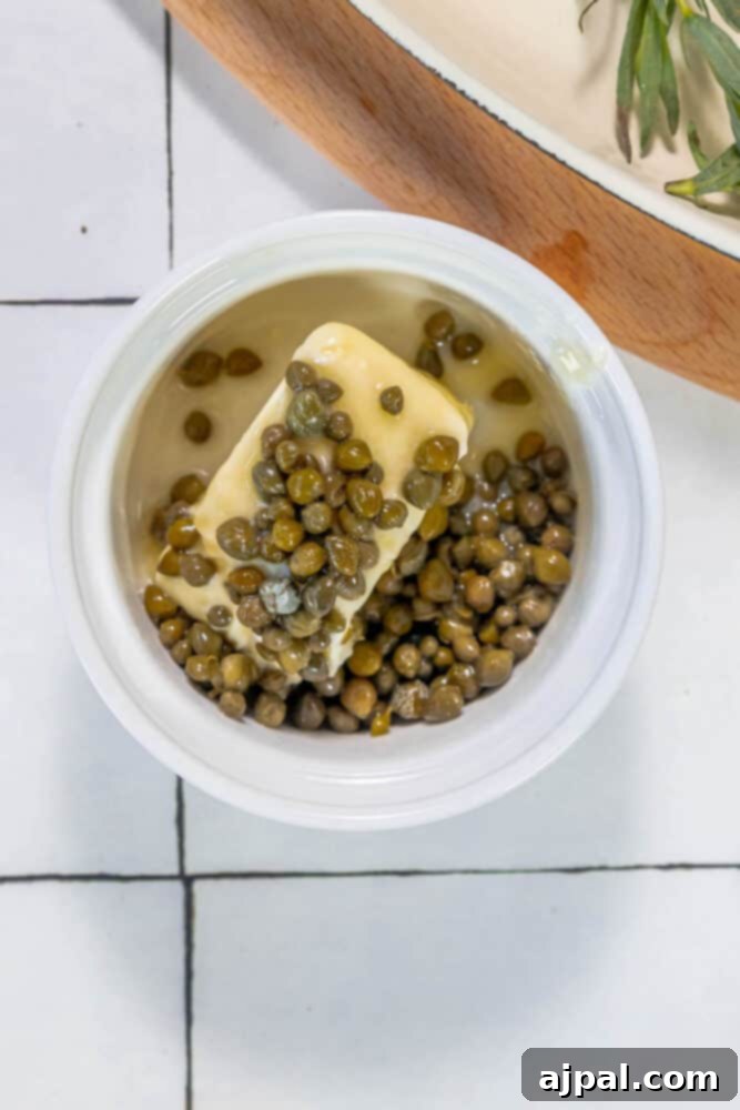 Roasted Branzino with Zesty Lemon-Caper Butter 9 A small bowl containing creamy butter mixed with briny capers, ready to be spread over the fish.
