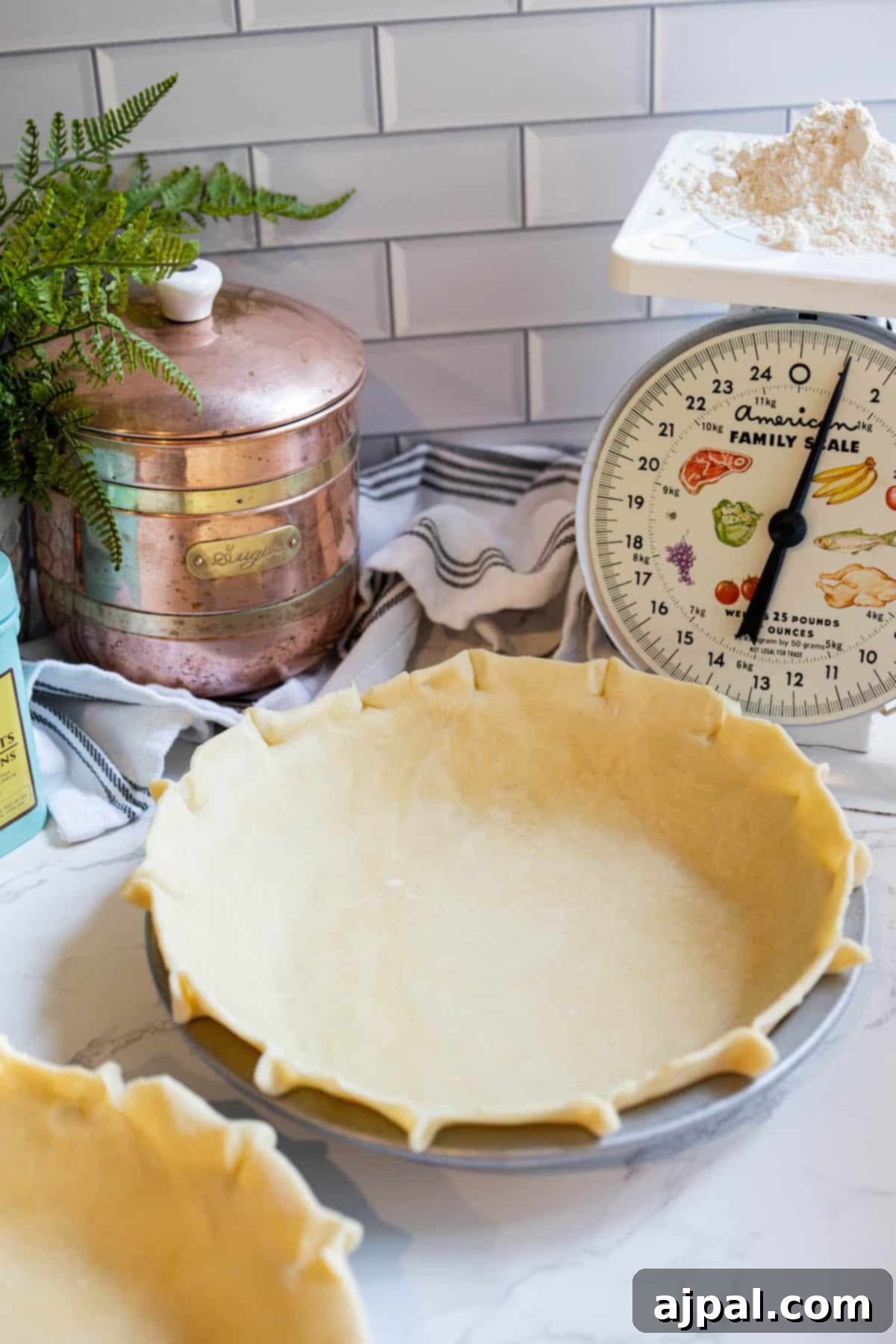 Two easy pie crusts on a counter next to a scale.