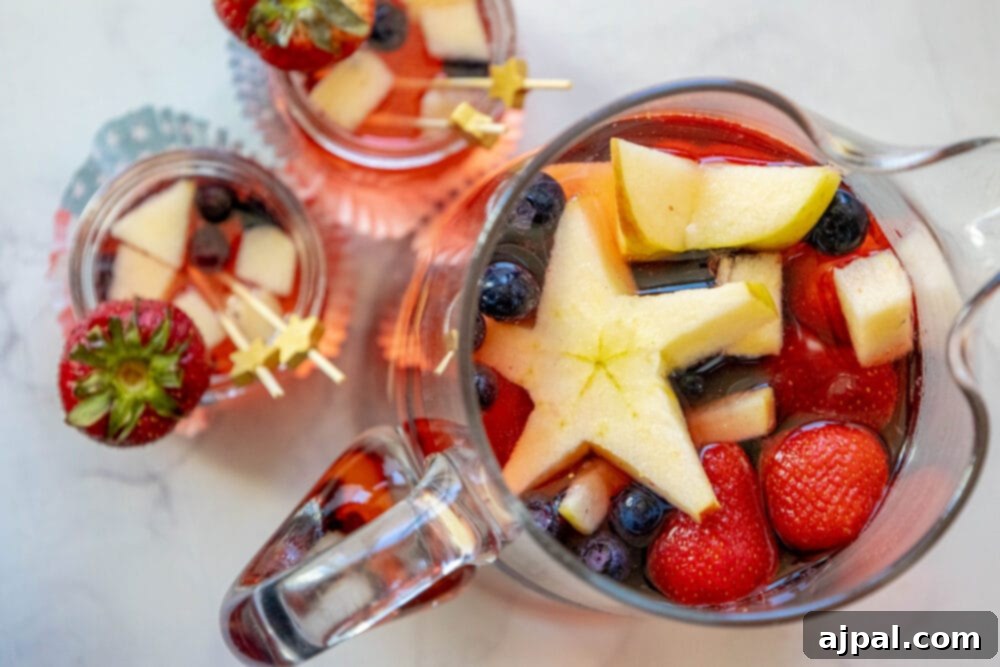 Stars and Stripes Celebration Punch 11 punch with strawberries, blueberries, and apples cut into star shapes in a pitcher and small glasses on a table