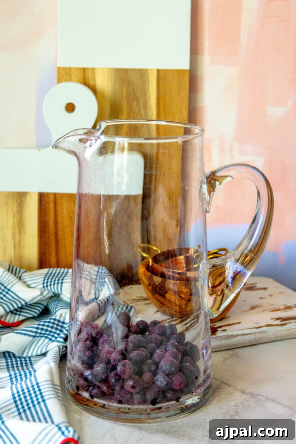 Stars and Stripes Celebration Punch 3 A patriotic glass pitcher filled with blueberries on a counter, perfect for a 4th of July celebration.