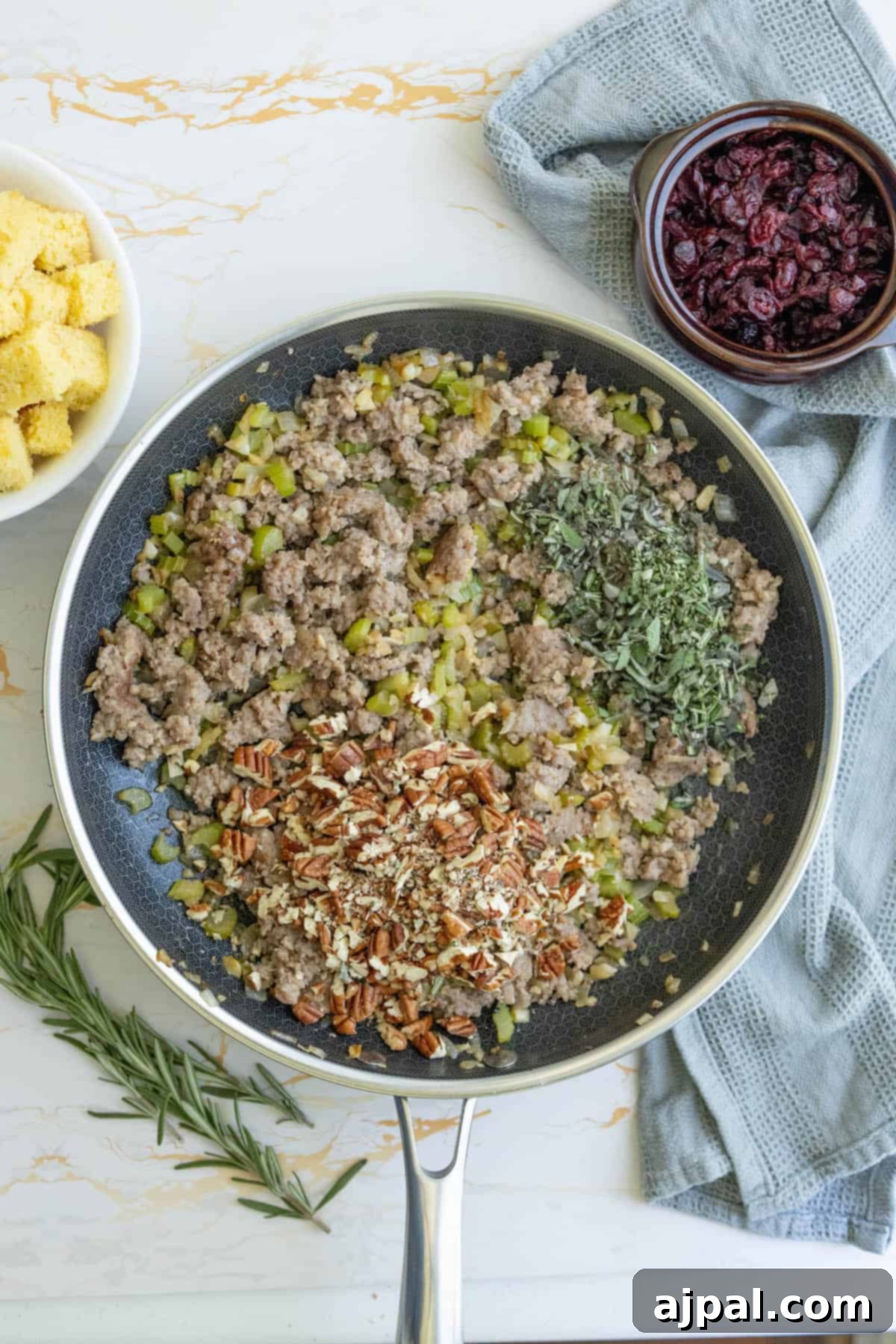 Hearty Sausage Cornbread Dressing 8 A frying pan full of browned sausage and vegetables, seasoned with fresh herbs and spices.