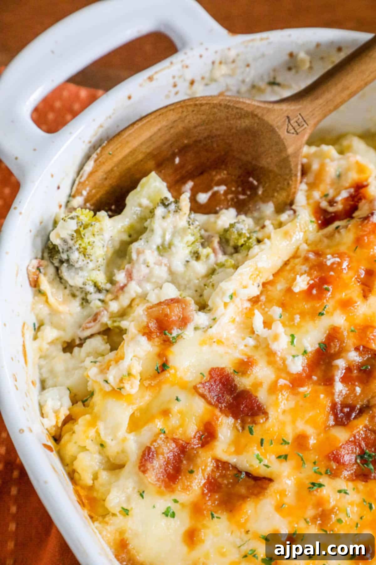A large baking dish filled with a creamy broccoli, cauliflower, and bacon casserole, topped with melted cheese, ready for serving.