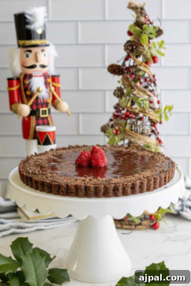 A slice of silky chocolate tart on a white dessert plate, ready to be served.