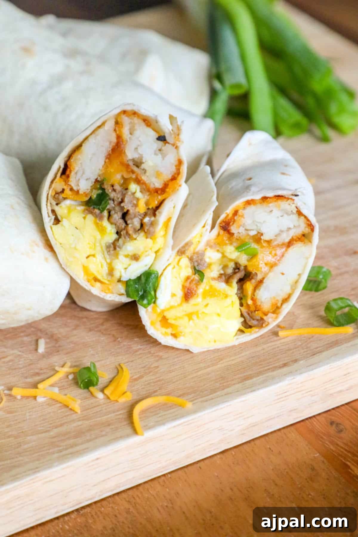 Grab-and-Go Breakfast Burritos 8 A vibrant freezer breakfast burrito, sliced in half to reveal its rich, savory fillings, presented on a wooden cutting board.