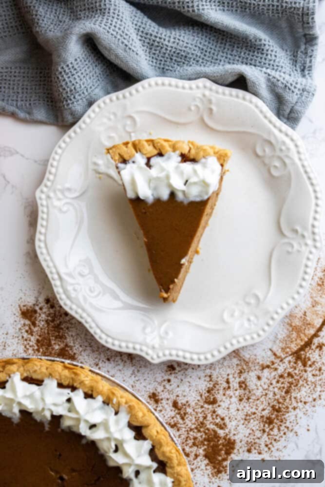 A close-up of a slice of pumpkin pie, revealing its smooth texture and rich, orange hue, with a hint of crust.