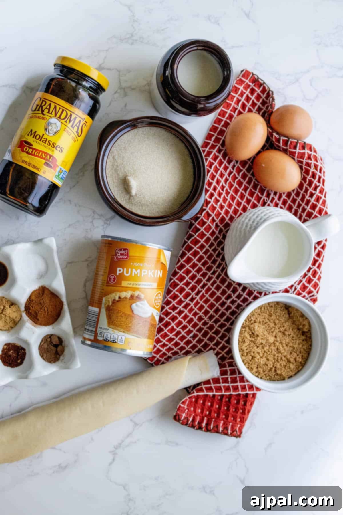 All the fresh ingredients for a delicious pumpkin pie, including pumpkin puree, spices, and a pie crust, neatly arranged on a marble countertop.