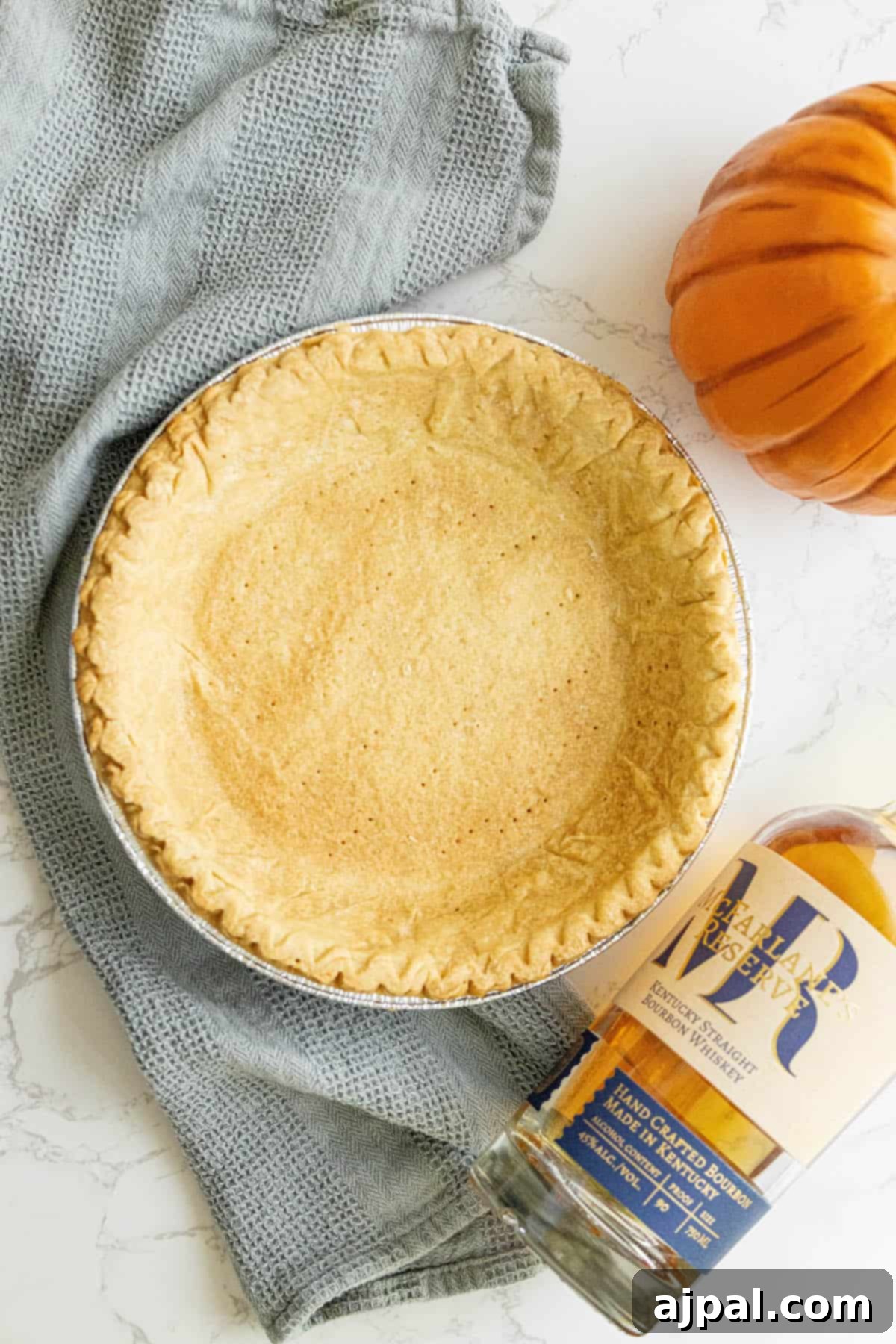 A spicy pumpkin pie sitting next to a bottle of bourbon, suggesting an adult twist on the classic dessert.